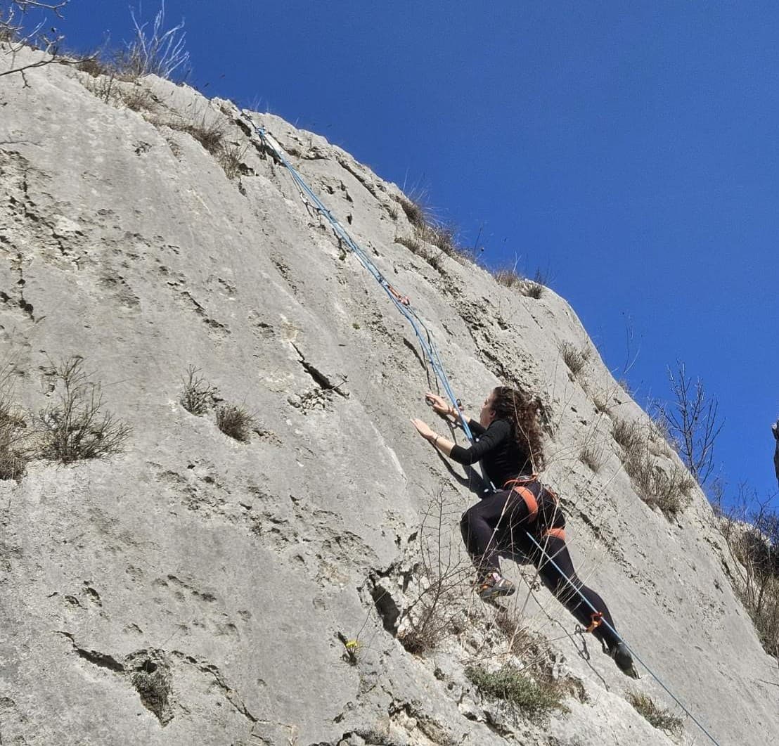 A woman rock climbing beneath a clear blue sky